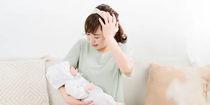 赤ちゃんを抱いて頭を抱える女性